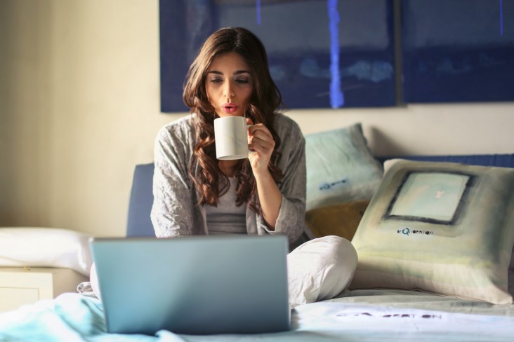 Woman drinks out of mug while on laptop