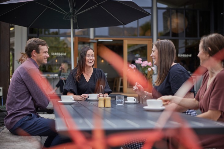 Team members sit chatting at an cafe outdoor table